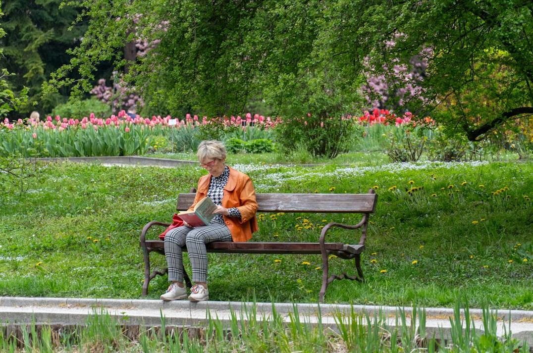 Woman reading a book outdoors on a park bench