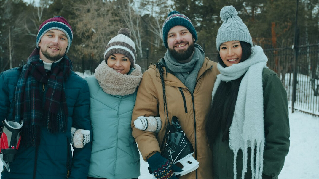 Group of five adults standing together outdoors smiling