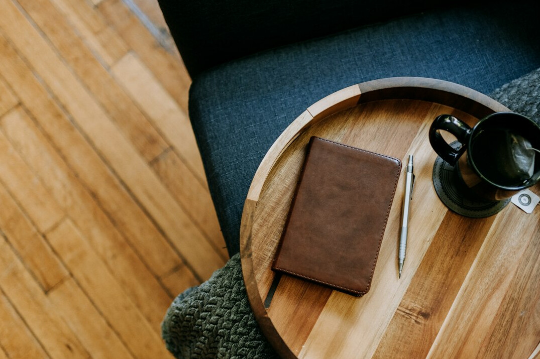 Wooden desk with an open notebook, pen and cup of coffee